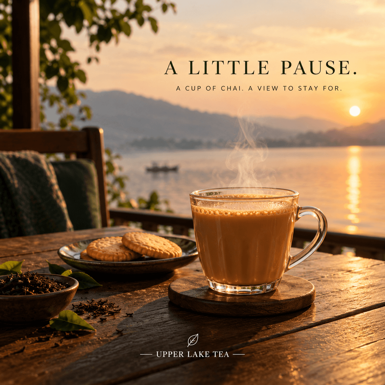 A glass of chai with biscuits on a wooden table by the lake at sunset