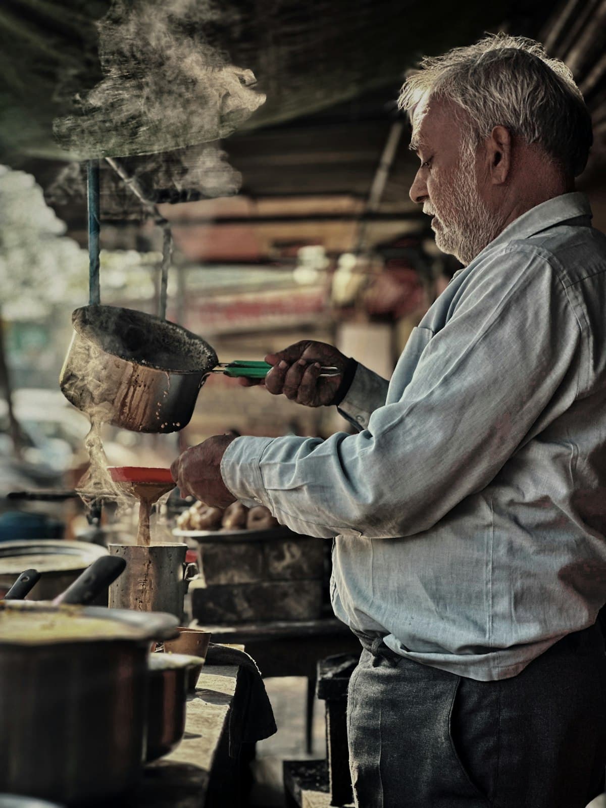 A chaiwala straining fresh chai at his stall